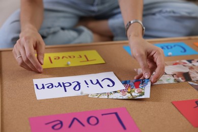 Photo of Woman creating vision with different photos and other elements board indoors, closeup