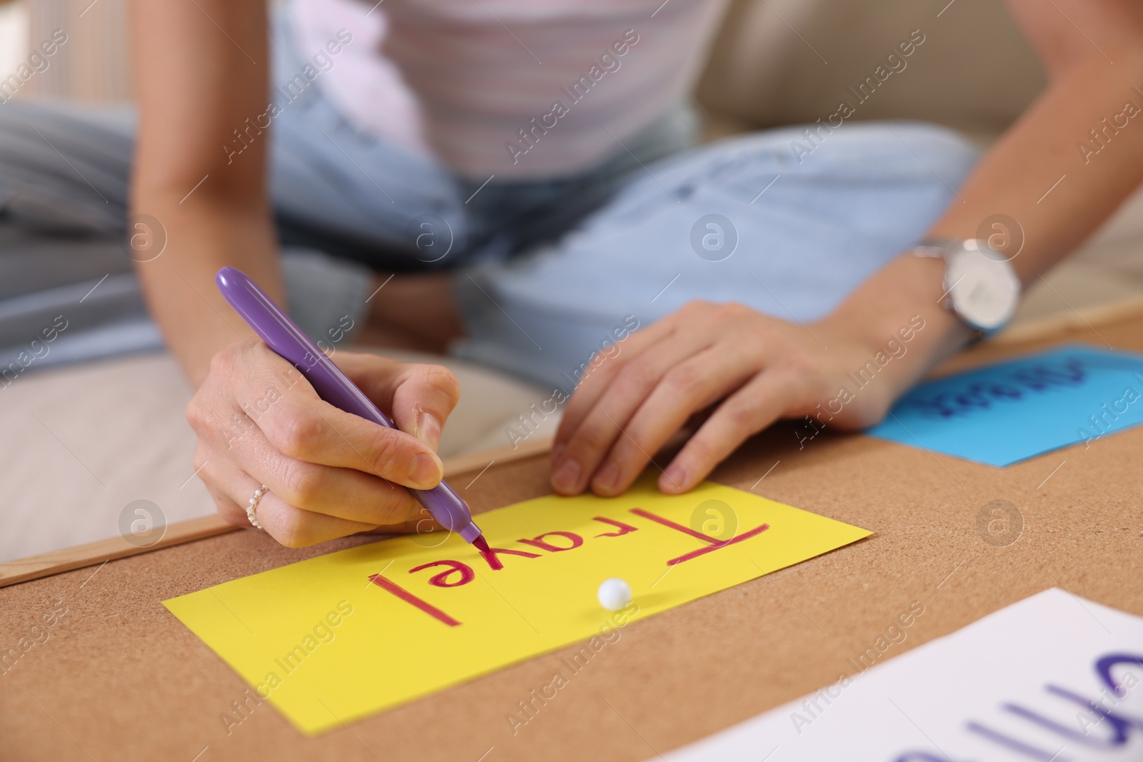 Photo of Creating vision board. Woman writing word Travel on card indoors, closeup