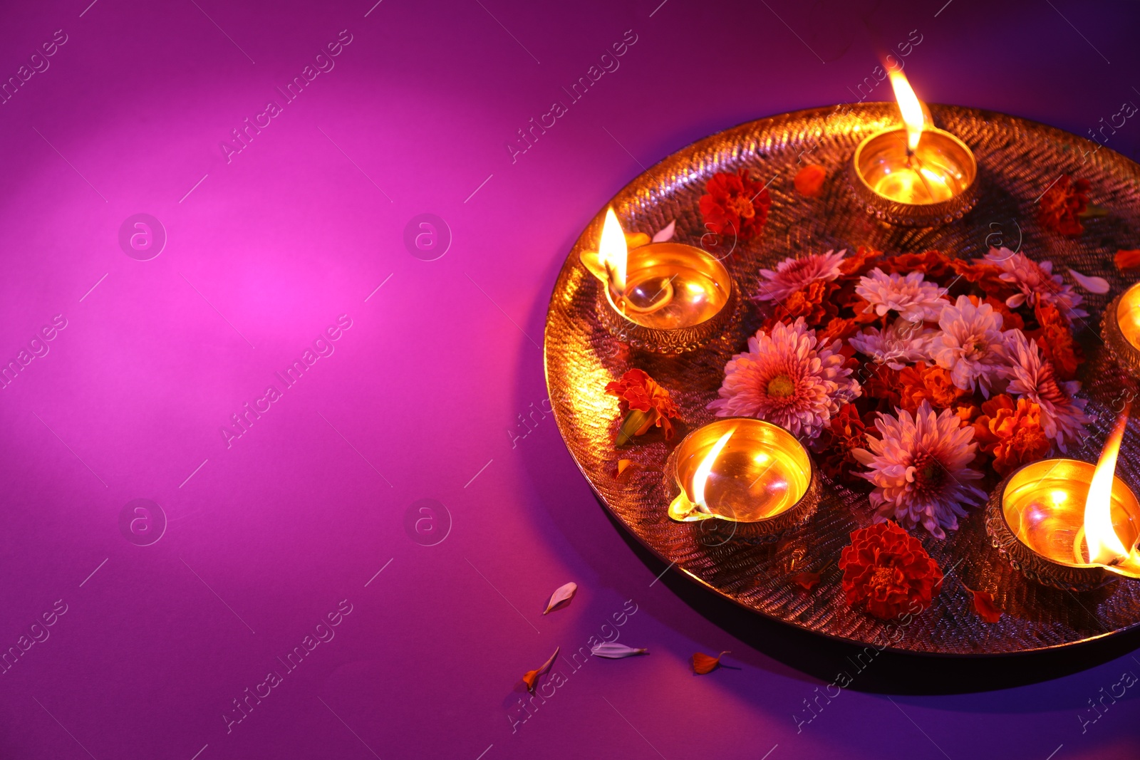 Photo of Diwali celebration. Diya lamps and beautiful flowers on color background, space for text