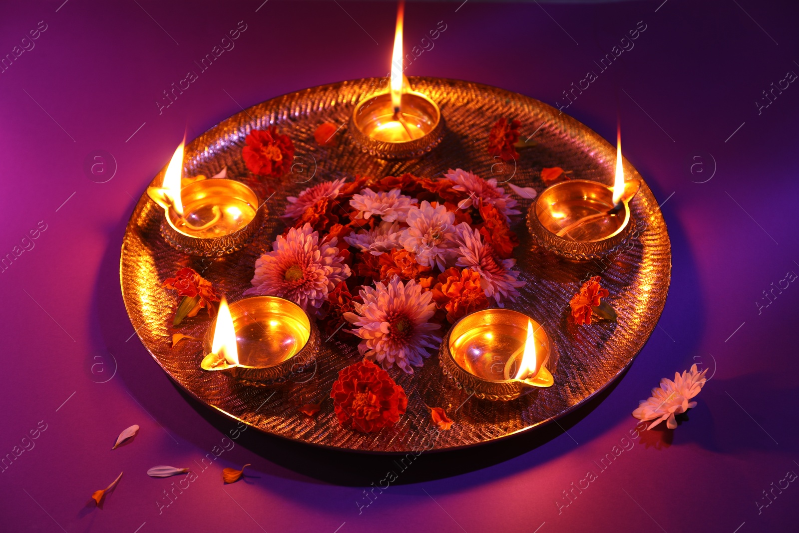 Photo of Diwali celebration. Diya lamps and beautiful flowers on color background