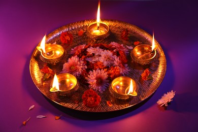 Photo of Diwali celebration. Diya lamps and beautiful flowers on color background