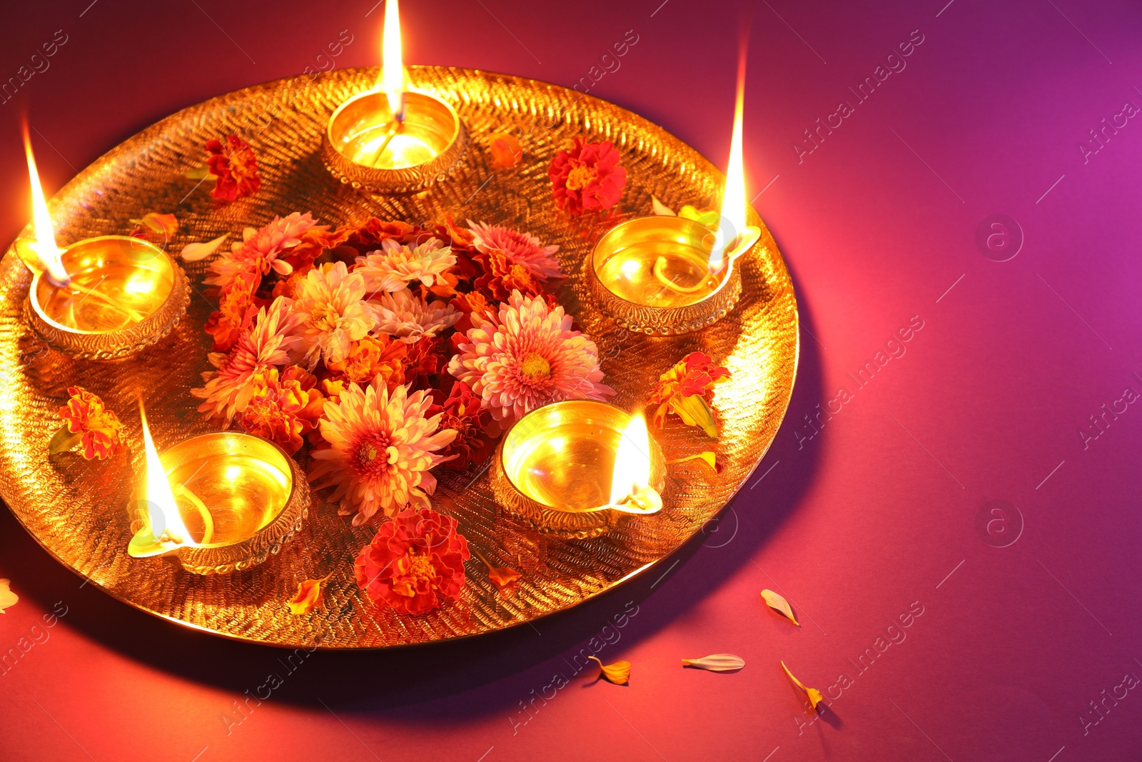 Photo of Diwali celebration. Diya lamps and beautiful flowers on color background