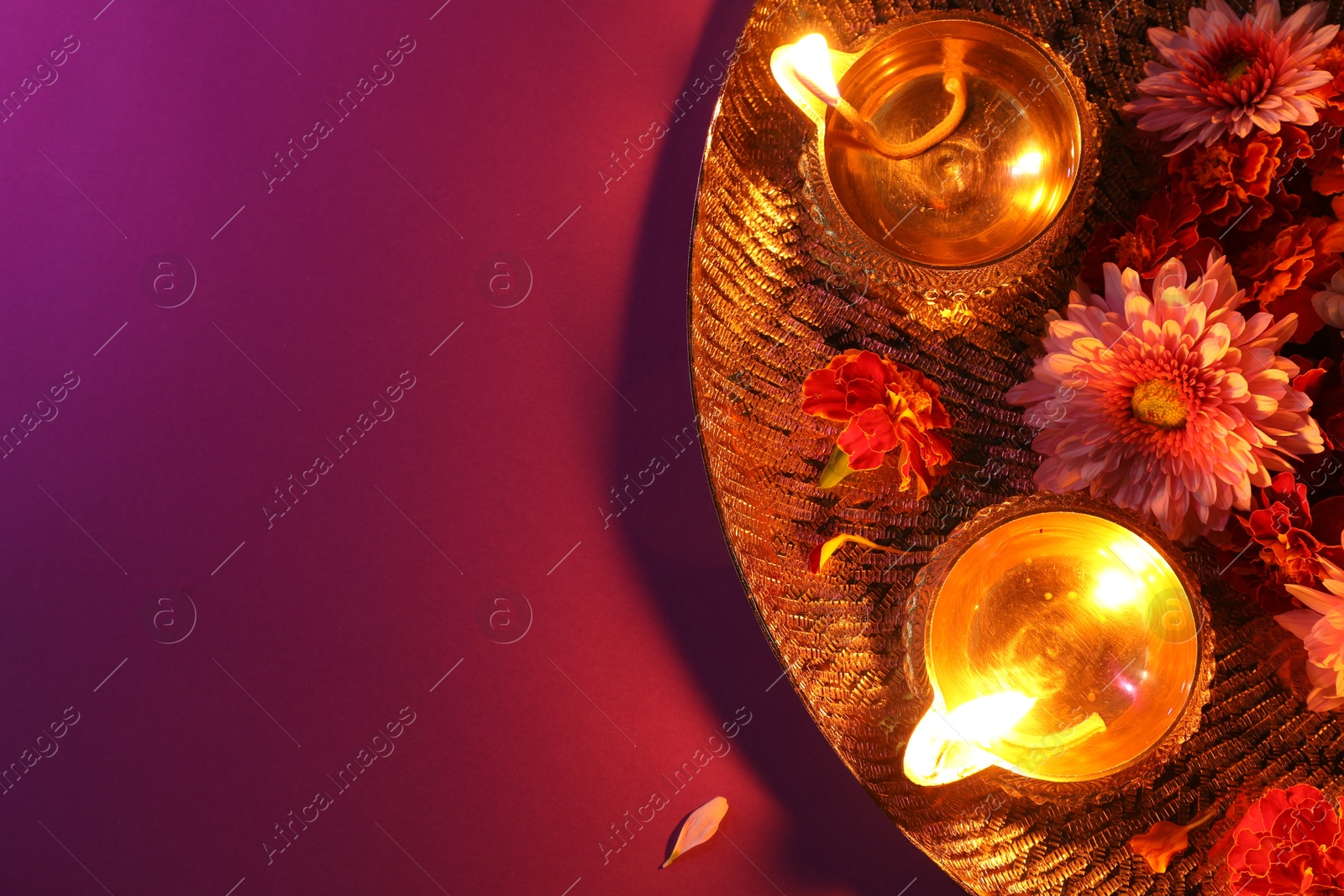 Photo of Diwali celebration. Diya lamps and beautiful flowers on color background, top view. Space for text