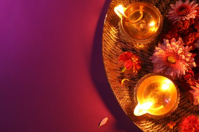 Photo of Diwali celebration. Diya lamps and beautiful flowers on color background, top view. Space for text