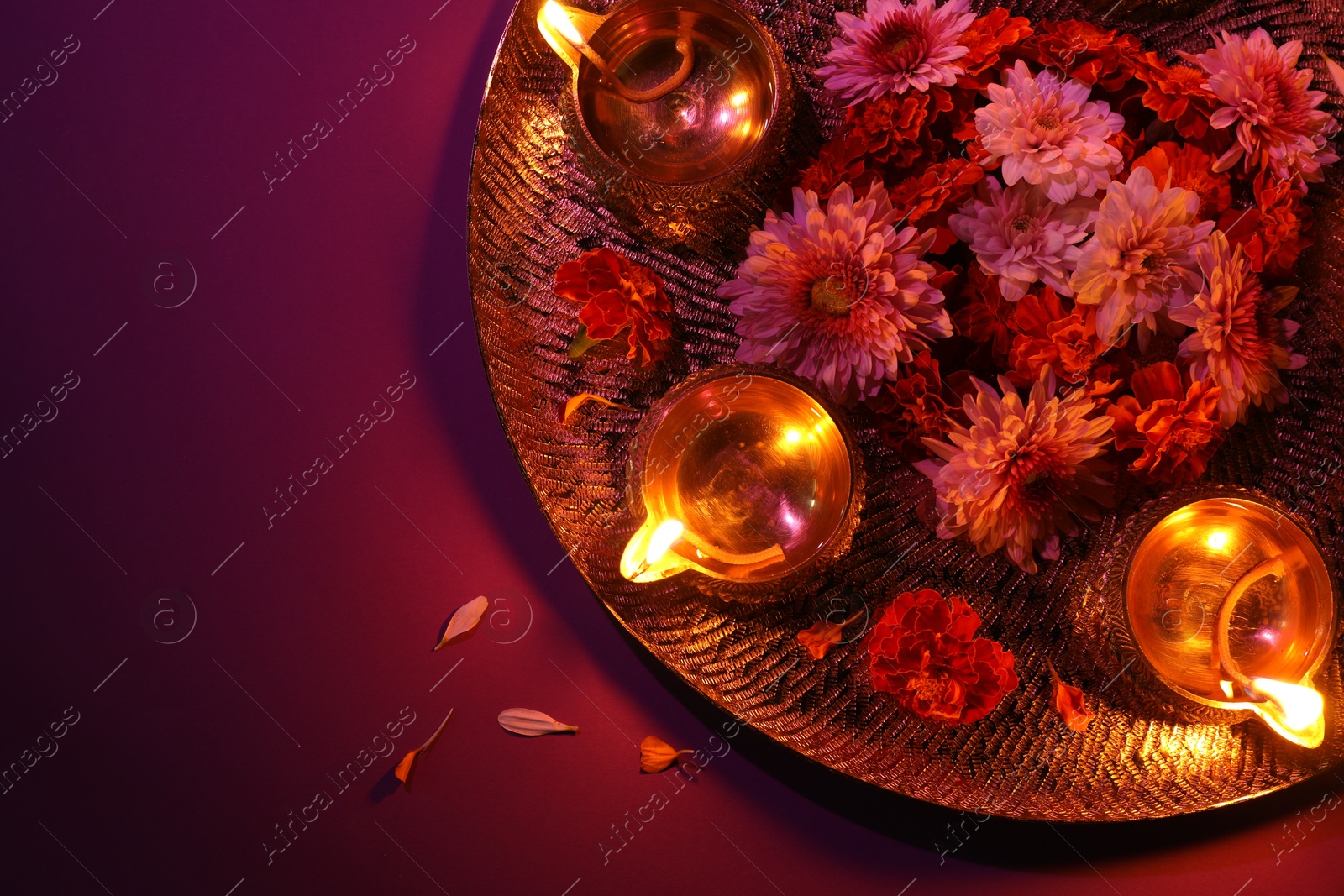 Photo of Diwali celebration. Diya lamps and beautiful flowers on color background, top view. Space for text