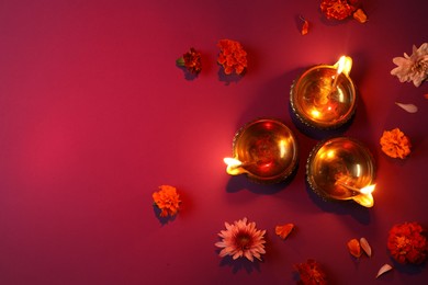 Photo of Diwali celebration. Diya lamps and beautiful flowers on color background, flat lay. Space for text