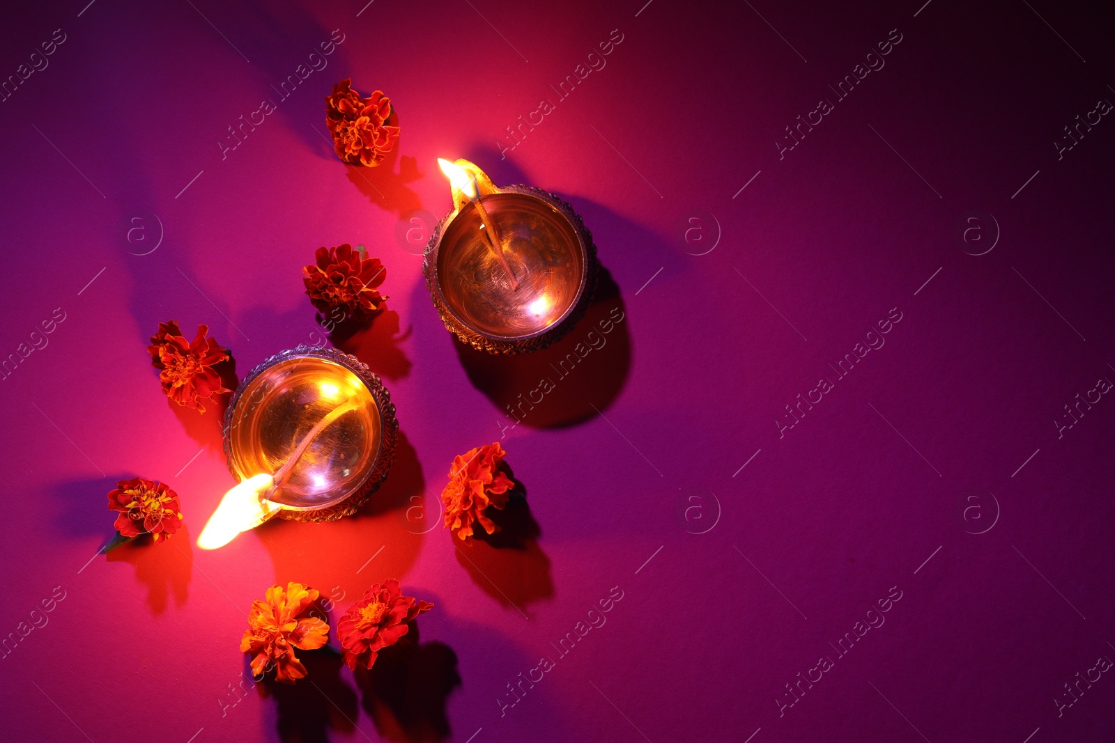 Photo of Diwali celebration. Diya lamps and beautiful flowers on color background, flat lay. Space for text