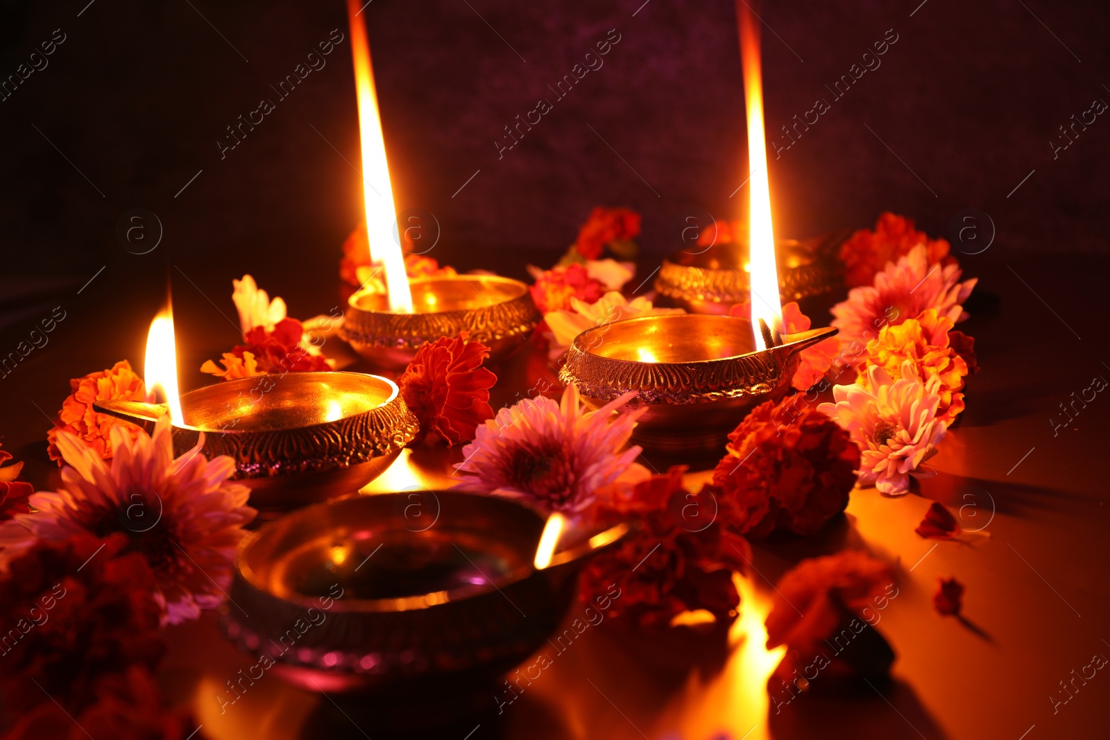 Photo of Diwali celebration. Diya lamps and beautiful flowers on dark background