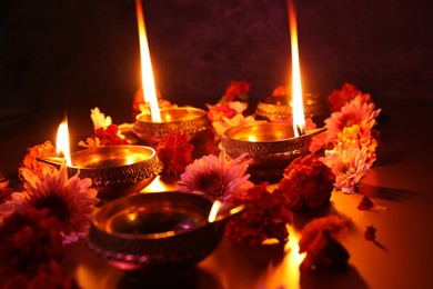 Photo of Diwali celebration. Diya lamps and beautiful flowers on dark background