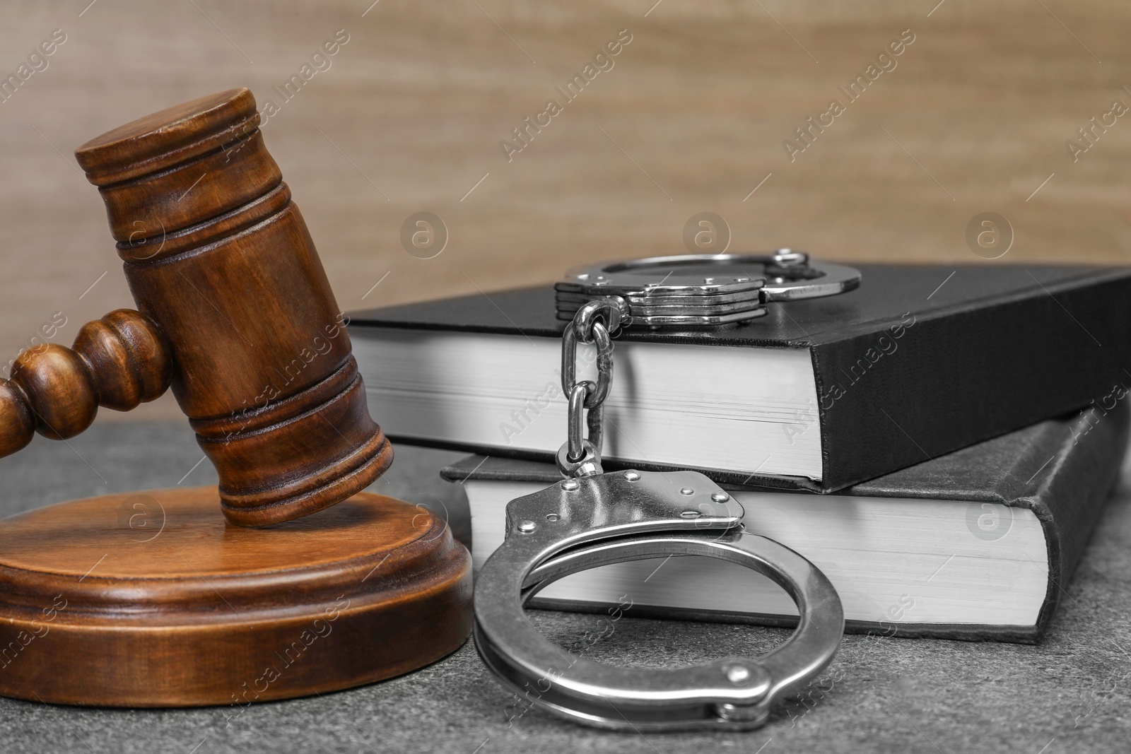 Photo of Books, judge's gavel and handcuffs on gray textured table, closeup