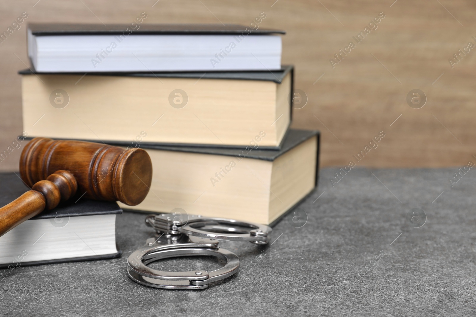 Photo of Books, judge's gavel and handcuffs on gray textured table, closeup