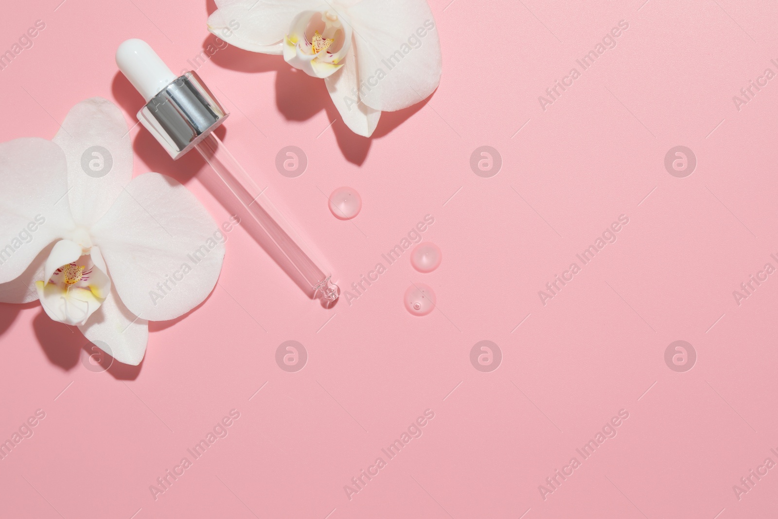 Photo of Beautiful orchid flowers and dropper with cosmetic product in water on pink background, flat lay. Space for text