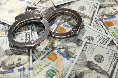 Handcuffs on pile of dollar banknotes, closeup