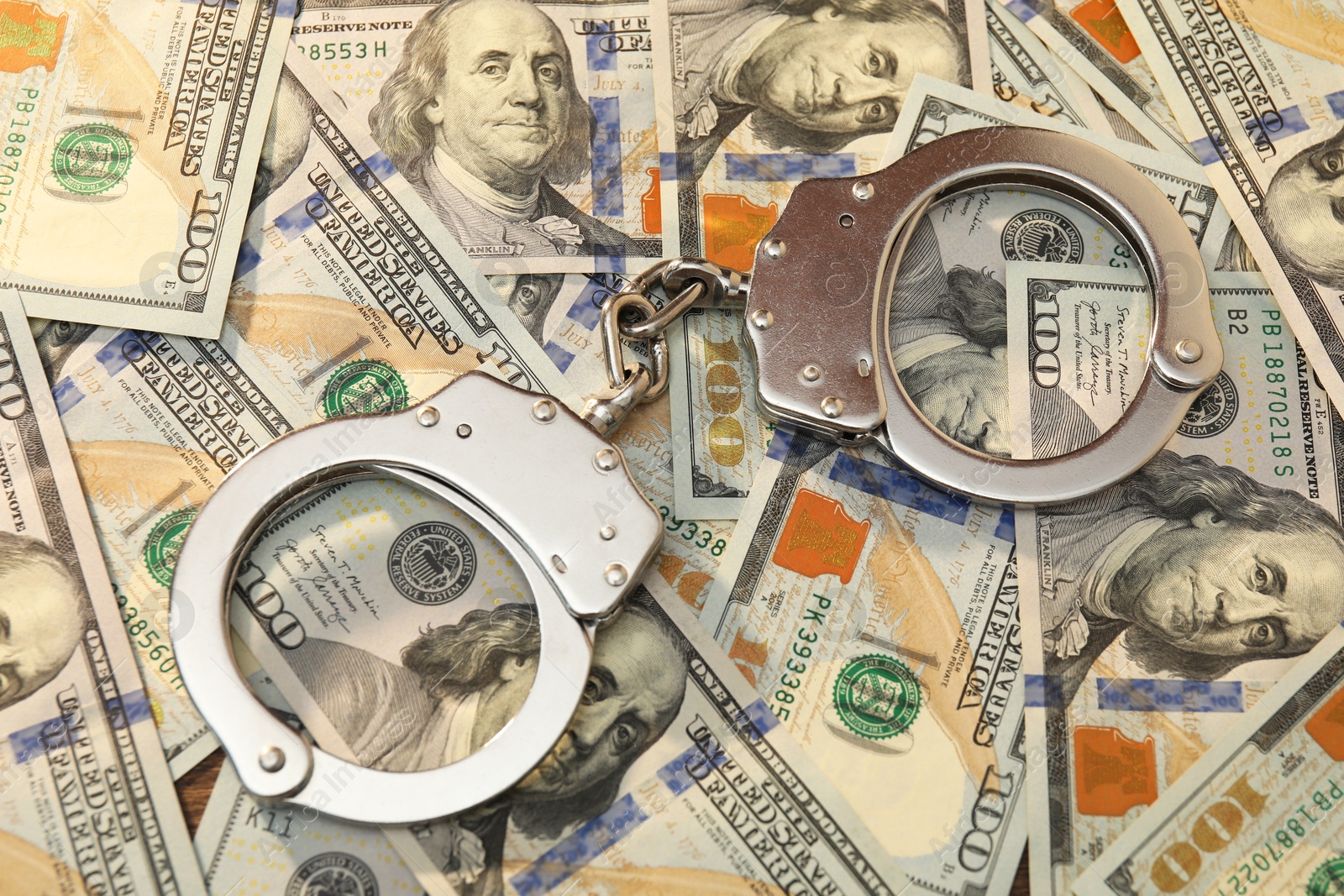 Photo of Handcuffs on pile of dollar banknotes, above view