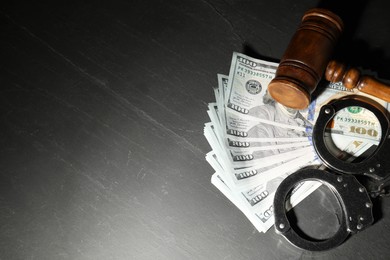 Photo of Handcuffs with dollar banknotes and wooden gavel on grey textured table. Space for text