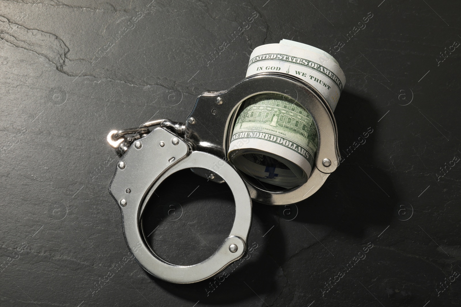 Photo of Handcuffs with dollar banknotes on grey textured table