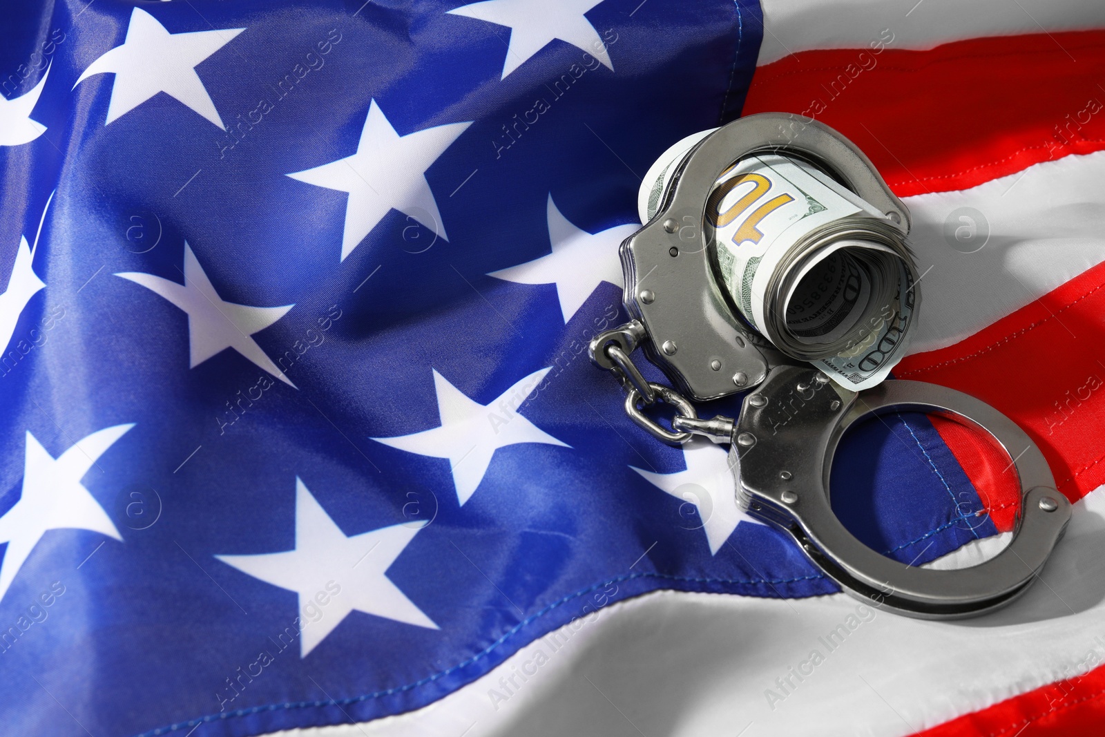 Photo of Handcuffs with dollar banknotes on American flag, space for text