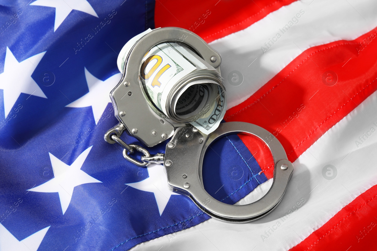 Photo of Handcuffs with dollar banknotes on American flag