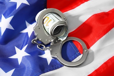 Handcuffs with dollar banknotes on American flag