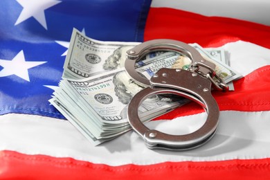 Photo of Handcuffs with dollar banknotes on American flag