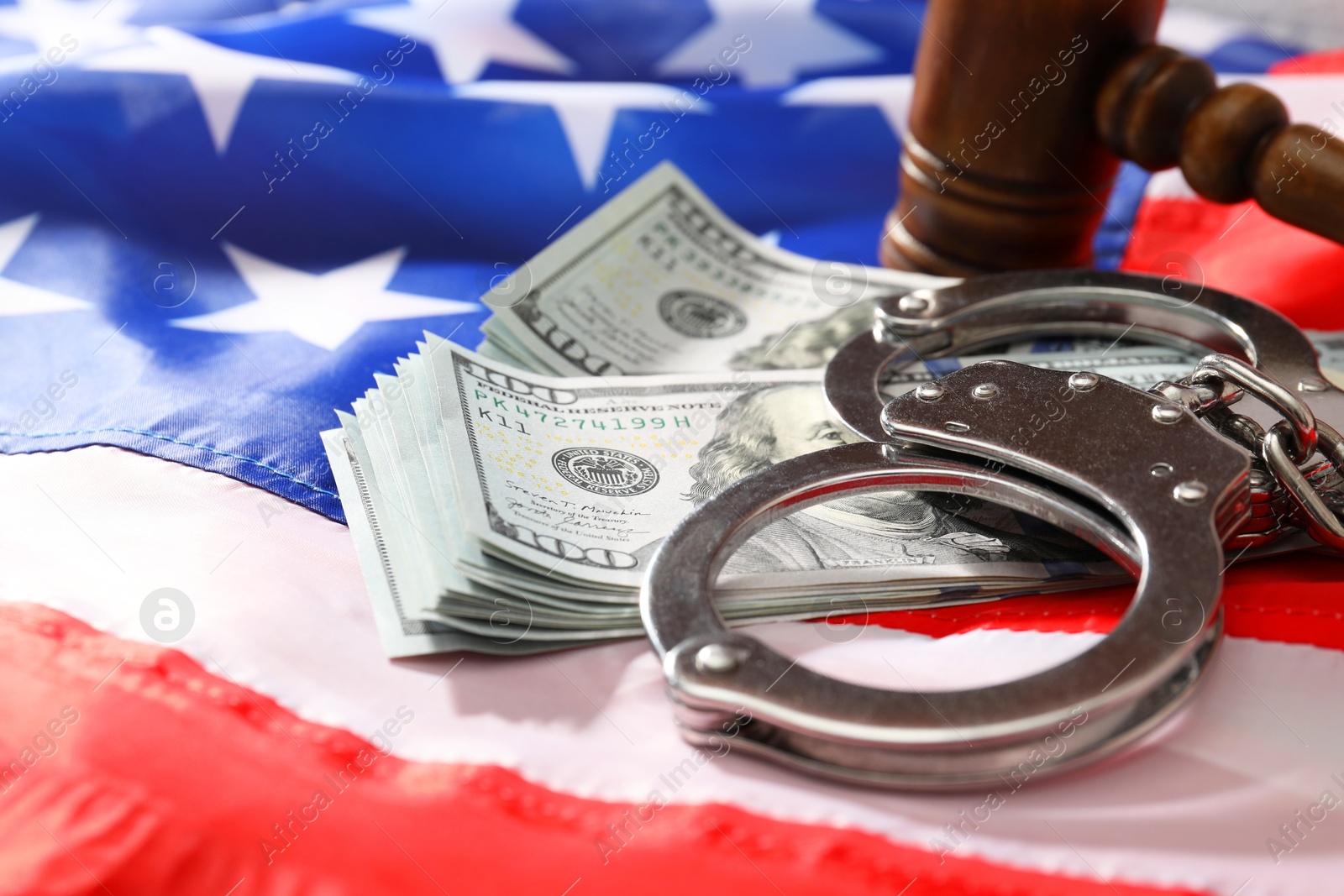 Photo of Handcuffs with dollar banknotes and wooden gavel on American flag