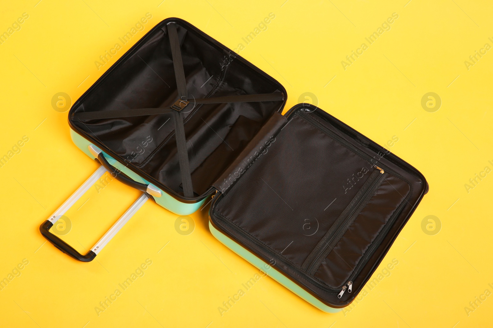 Photo of Open empty suitcase on yellow background, above view