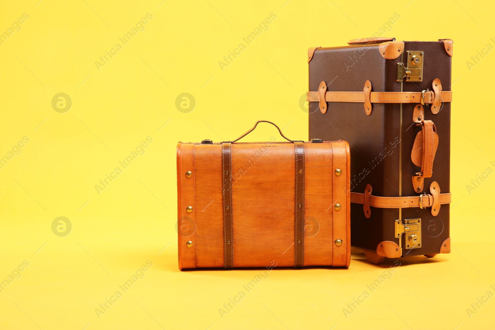 Photo of Two different brown suitcases on yellow background, space for text