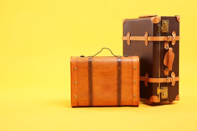 Photo of Two different brown suitcases on yellow background, space for text