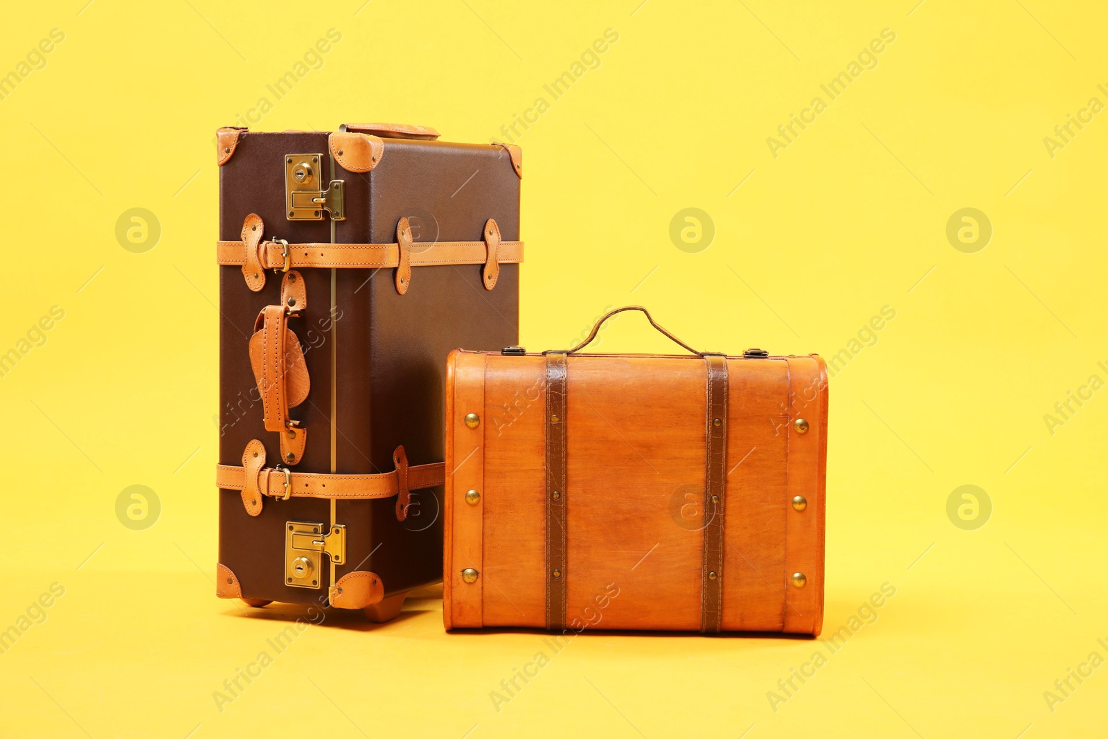 Photo of Two different brown suitcases on yellow background