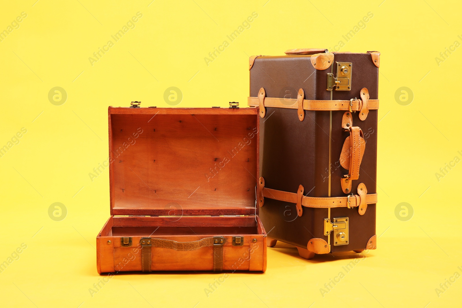 Photo of Two different brown suitcases on yellow background