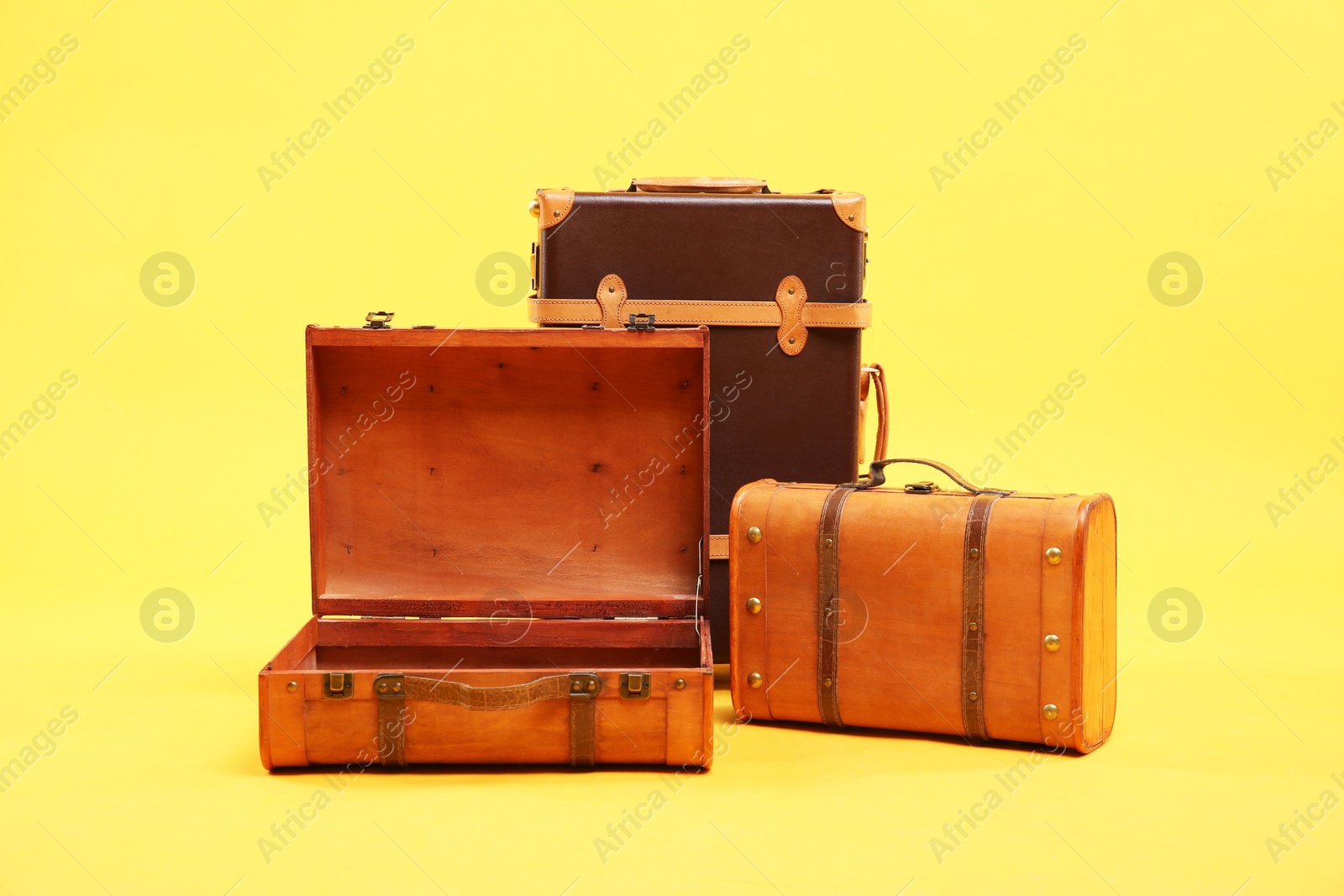 Photo of Three different brown suitcases on yellow background