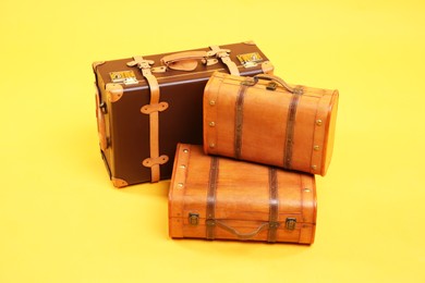 Photo of Three different closed suitcases on yellow background