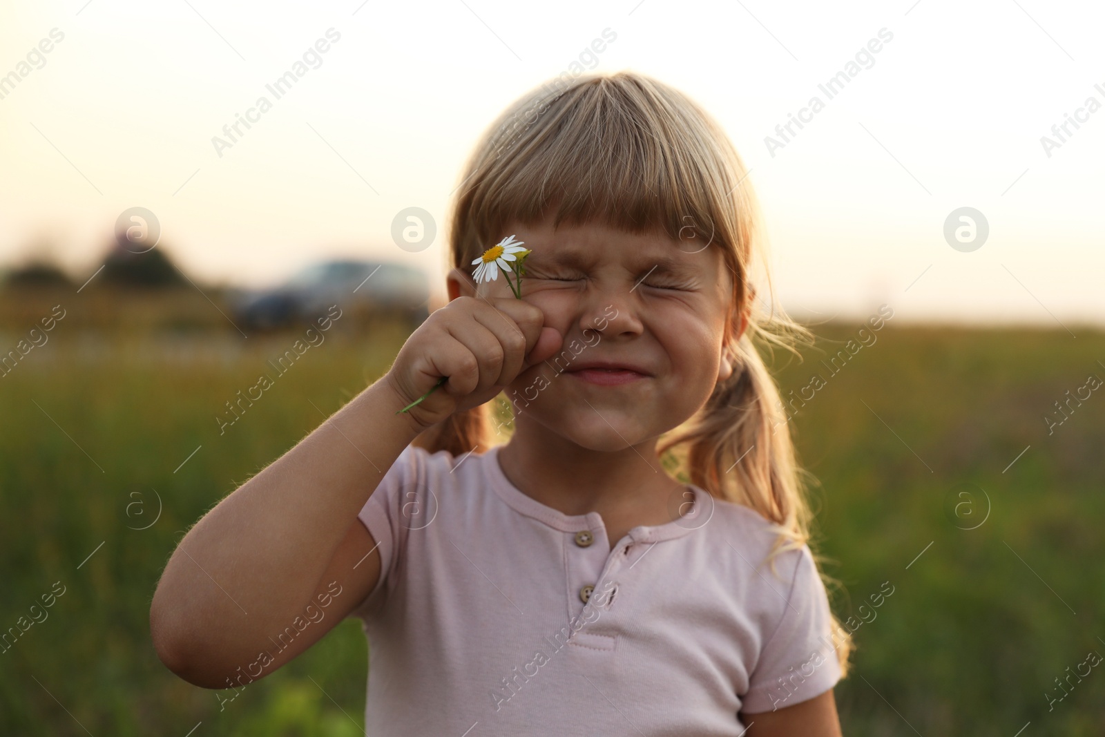 Photo of Cute little girl with flower at meadow. Child enjoying beautiful nature