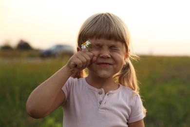 Photo of Cute little girl with flower at meadow. Child enjoying beautiful nature