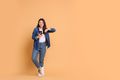 Photo of Smiling woman using smartphone on beige background