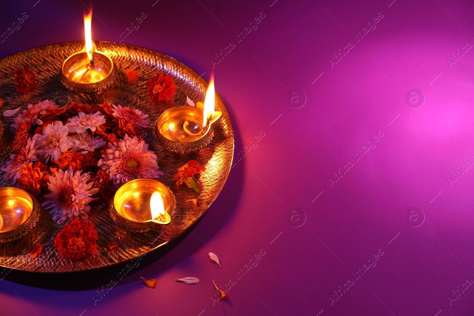 Photo of Diwali celebration. Diya lamps and beautiful flowers on color background, space for text