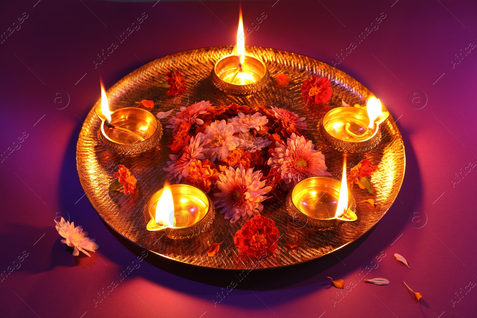 Photo of Diwali celebration. Diya lamps and beautiful flowers on color background