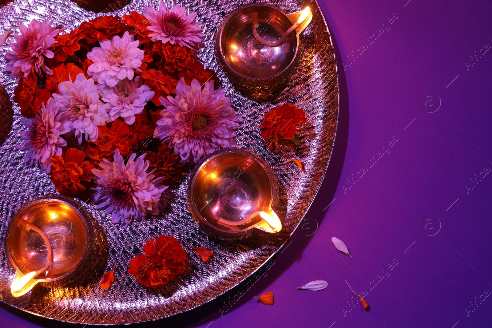 Photo of Diwali celebration. Diya lamps and beautiful flowers on color background, top view. Space for text