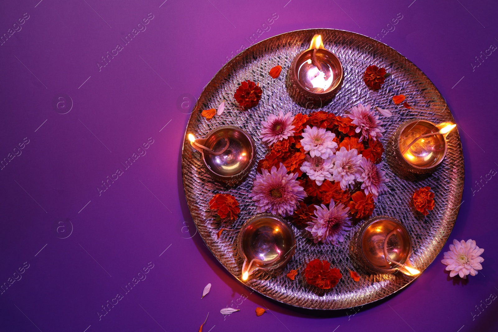 Photo of Diwali celebration. Diya lamps and beautiful flowers on color background, top view. Space for text