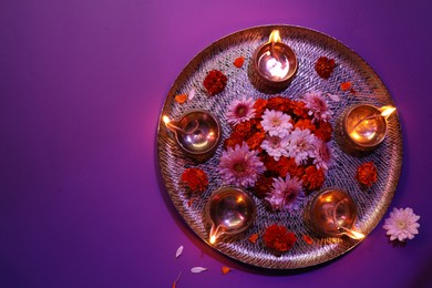 Photo of Diwali celebration. Diya lamps and beautiful flowers on color background, top view. Space for text