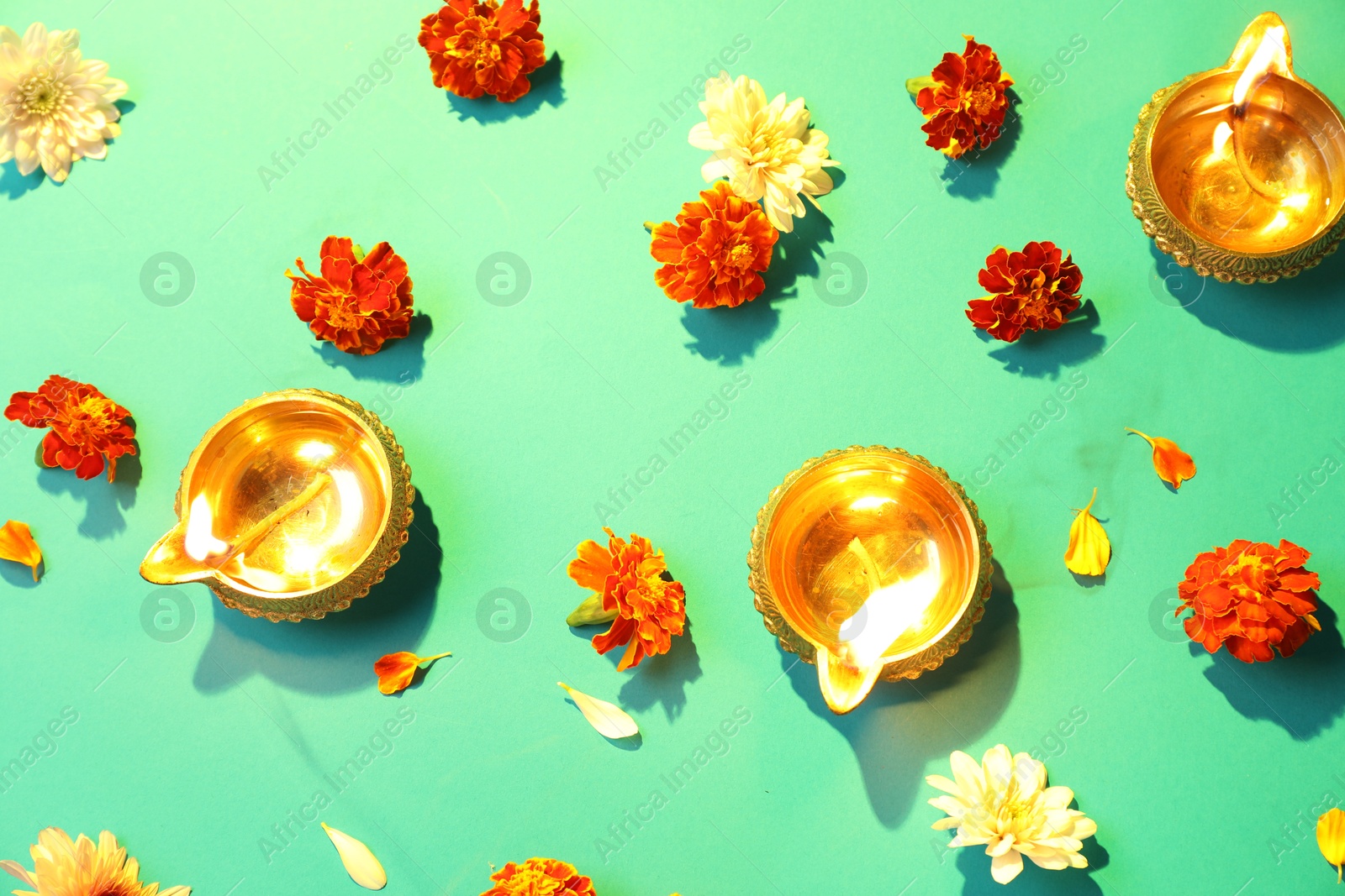 Photo of Diwali celebration. Diya lamps and beautiful flowers on bright background, flat lay