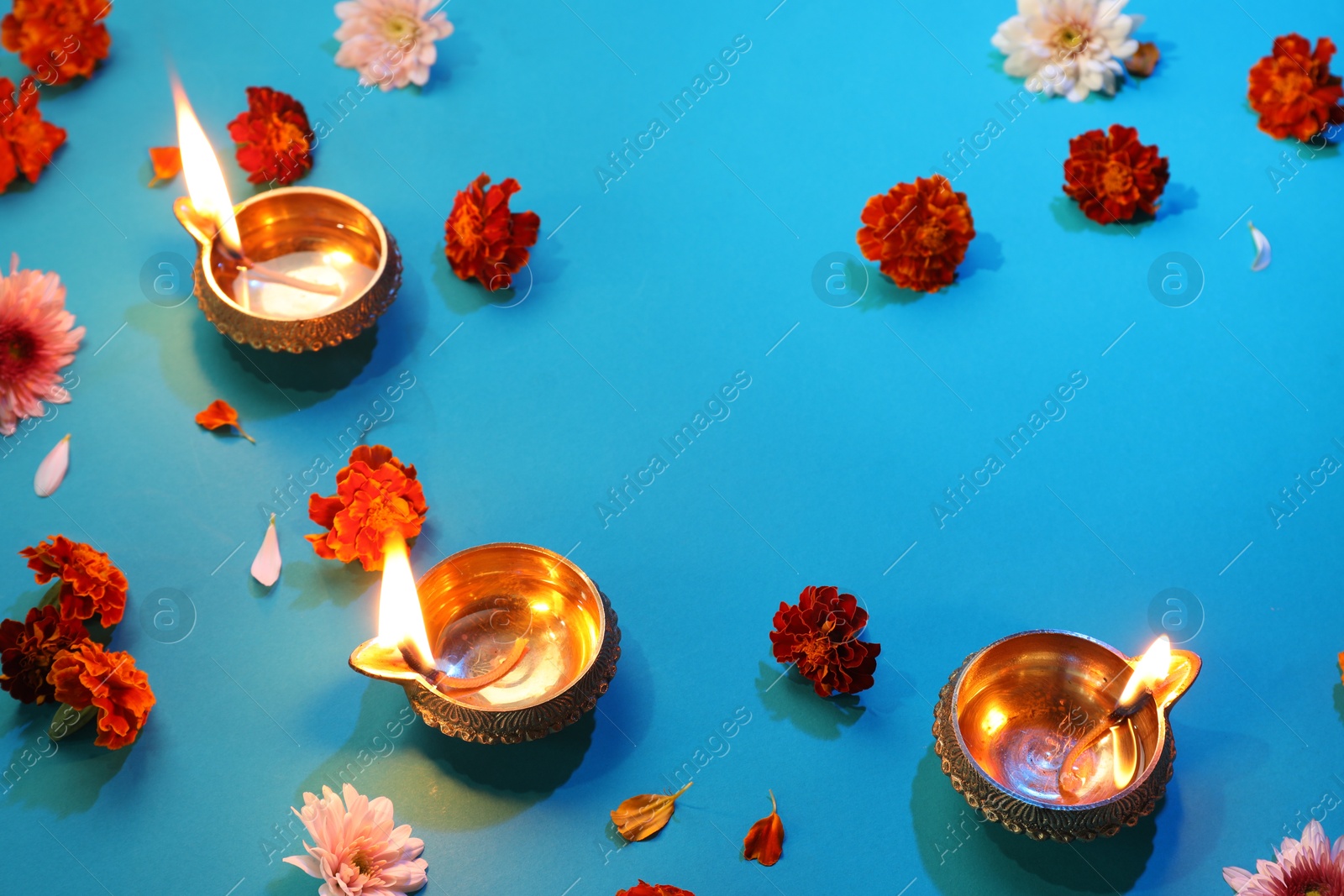 Photo of Diwali celebration. Diya lamps and beautiful flowers on blue background, above view