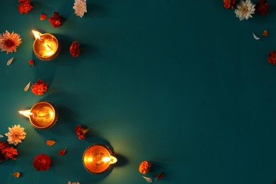 Photo of Diwali celebration. Diya lamps and beautiful flowers on color background, flat lay. Space for text