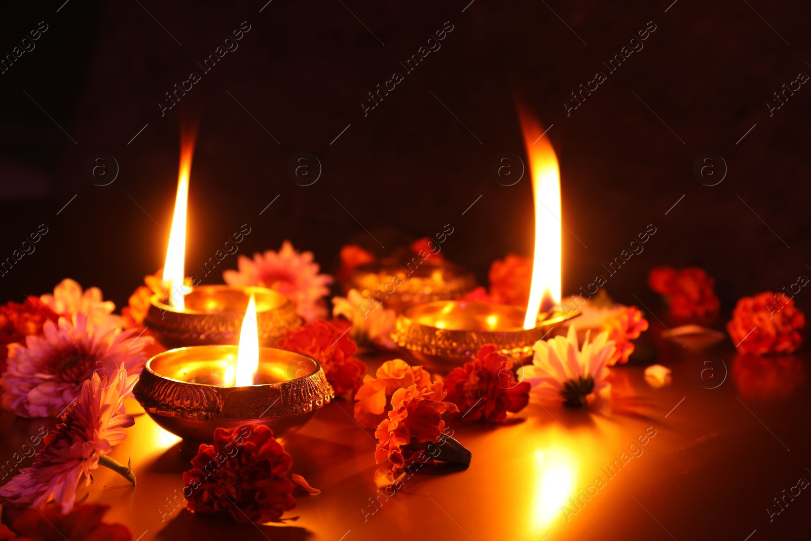 Photo of Diwali celebration. Diya lamps and beautiful flowers on dark background