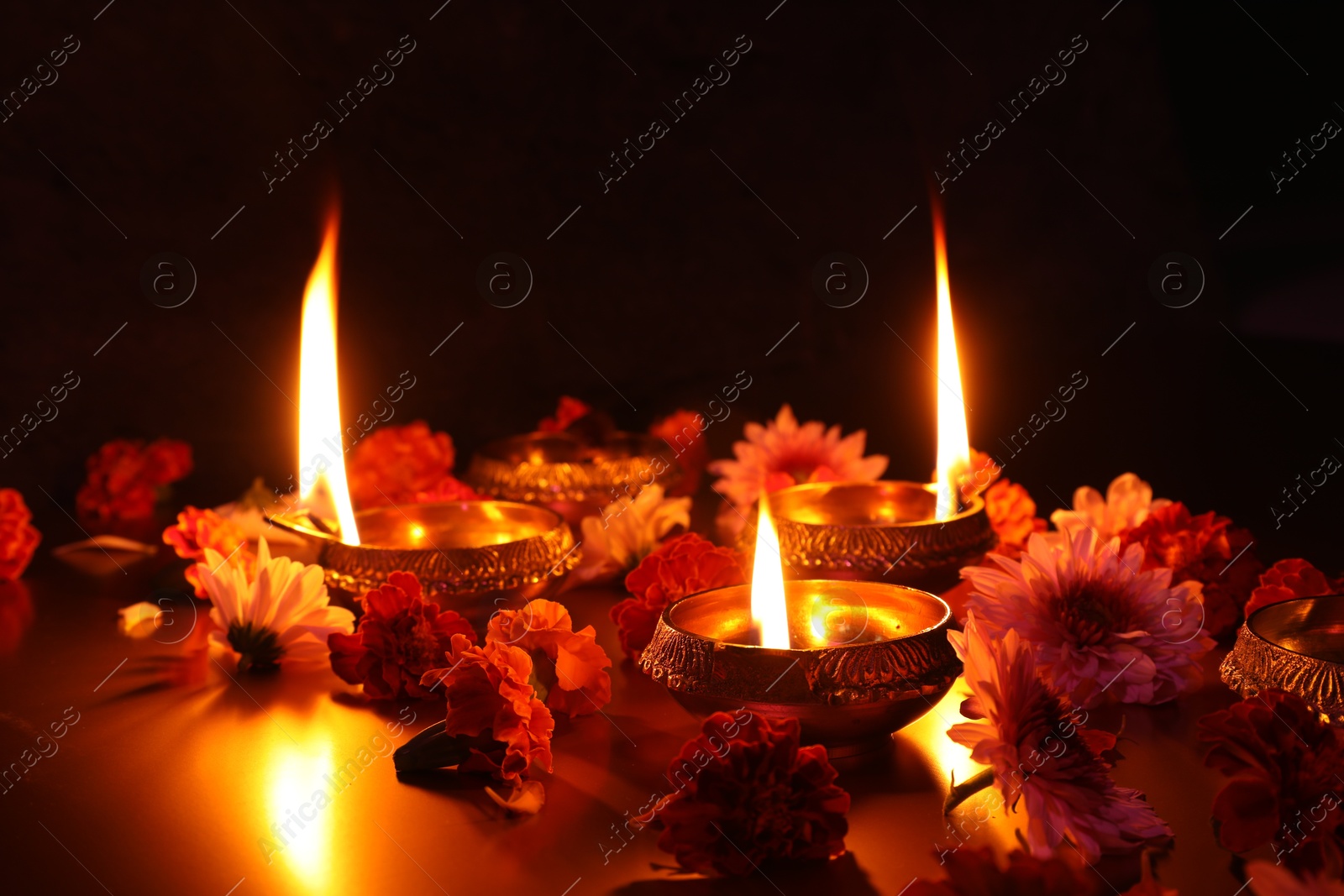 Photo of Diwali celebration. Diya lamps and beautiful flowers on dark background