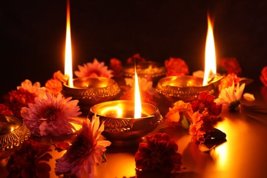 Photo of Diwali celebration. Diya lamps and beautiful flowers on dark background