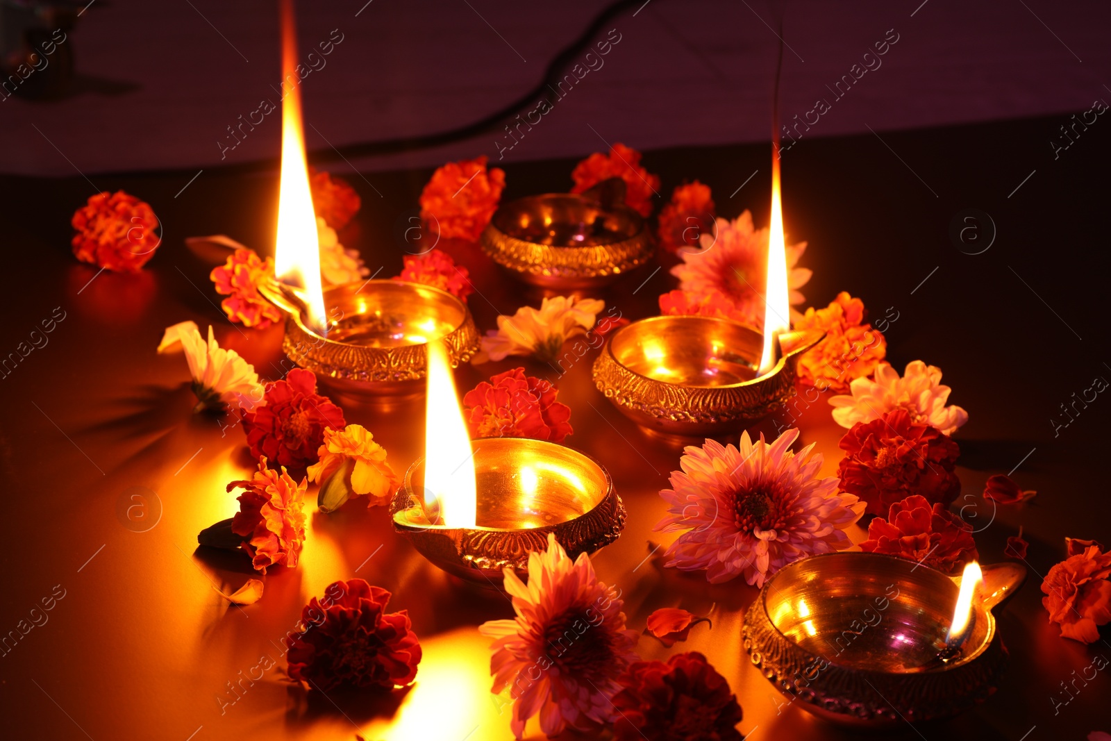 Photo of Diwali celebration. Diya lamps and beautiful flowers on dark background