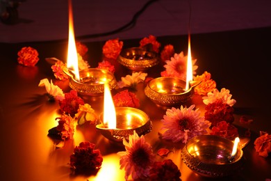 Photo of Diwali celebration. Diya lamps and beautiful flowers on dark background