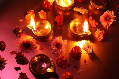 Photo of Diwali celebration. Diya lamps and beautiful flowers on color background, above view