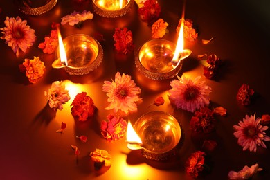 Photo of Diwali celebration. Diya lamps and beautiful flowers on color background, above view